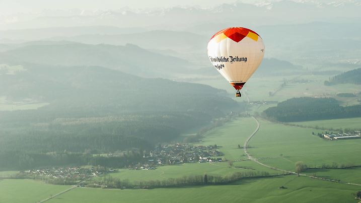 Ein Heissluftballon fährt in den frühen Morgenstunden über die Allgäulandschaft bei Friesenhofen, Baden Württemberg, Deutschland. Bei einer Fahrt mit dem Heissluftballon über das Allgäu zwischen Wangen und Leutkirch.  
