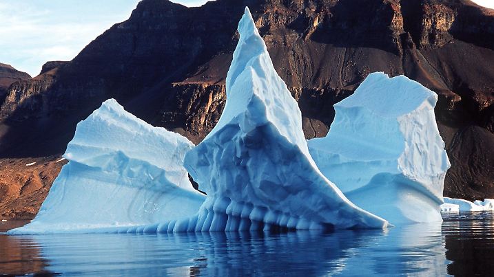 ARCHIV - Ein bizarr geformter Eisberg spiegelt sich im Scoresby Sund im Wasser des Atlantischen Ozeans (Archivfoto von 2001). Die Pole sind wichtig für das Leben auf der ganzen Welt. Veränderungen dort wirken sich auf Meeresspiegel und Klima ebenso aus wie auf Fischfang, Rohstoffförderung und viele Tier- und Pflanzenarten. Um so bedrohlicher ist es, dass sich die steigenden Temperaturen vor allem in diesen Regionen bemerkbar machen. In den vergangenen 50 Jahren habe sich die Lufttemperatur in der Arktis mit 1,1 Grad doppelt so stark erhöht wie im globalen Durchschnitt, sagte der Leiter des Fachbereichs Klimasystem am Alfred-Wegener-Institut für Polar- und Meeresforschung (AWI) in Bremerhaven bei einer Tagung in Frankfurt Anfang Januar 2007. (zu dpa-KORR "Die Pole: Schlüsselregionen für das Weltklima" vom 15.01.2007) +++(c) dpa - Bildfunk+++