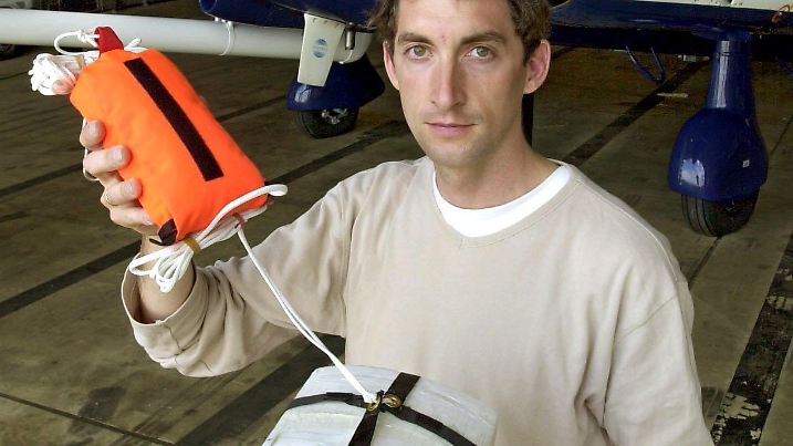 Gerko Wende, Mitarbeiter des Forschungsprojekts "Vertikator", zeigt am 4.6.2002 auf dem Baden-Airpark in Söllingen eine meteorologische Fallsonde. In der Sonde sind Geräte installiert, die im Flug Lufttemperatur und -feuchtigkeit messen. Etwa 30 mit Fallschirm versehene Sonden werden bei einem Messflug über entstehenden Gewitterwolken abgeworfen. Ein für wissenschaftliche Zwecke gebautes und mit Messinstrumenten bepacktes Flugzeug (Hintergrund) dient zur Ermittlung von Daten über Lufttemperatur, -feuchte, Wind und Turbulenzen. Unter Federführung des Institituts für Meteorologie und Klimaforschung in Karlsruhe wird mit Flugzeugen, Radargeräten, Ballonsonden und am Boden installierten Messgeräten der vertikale Austausch in der unteren Athmosphäre über dem Schwarzwald untersucht. Ziel sind präzisere Wettervorhersagen. |