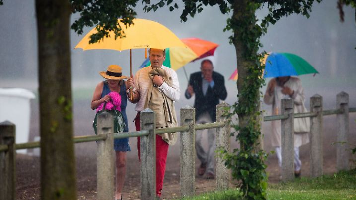 Besucher des zweiten Picknick-Konzerts im Landgestüt Redefin (Mecklenburg-Vorpommern) bei Ludwigslust gehen am 05.07.2014 im Gewitterregen zur Aufführung in der Reithalle. Das Konzert mit dem Württembergischen Kammerorchester Heilbronn findet im Rahmen der Festspiele Mecklenburg-Vorpommern statt. Foto: Jens Büttner/dpa +++(c) dpa - Bildfunk+++