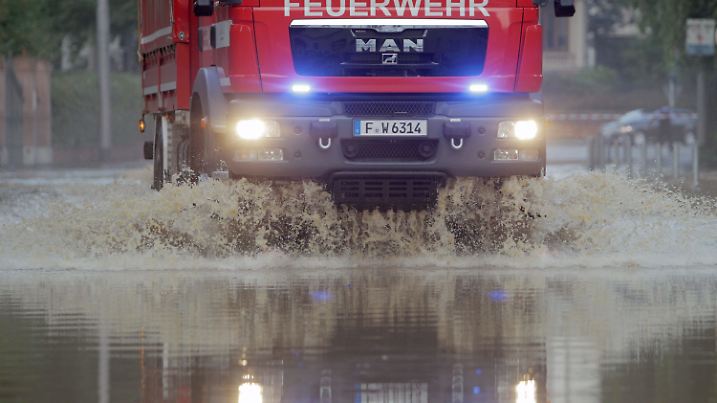 Ein Fahrzeug der Feuerwehr fährt am 11.07.2014 durch eine überflutete Straße in Wiesbaden (Hessen). Blitz, Donner und Starkregen haben in Hessen gewütet. Besonders heftige Unwetter gab es nach Polizeiangaben im Raum Wiesbaden, wo der Rambach über die Ufer trat. Foto: Fredrik von Erichsen/dpa +++(c) dpa - Bildfunk+++