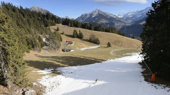 epa05080074 A snowboarder in action on a ski slope covered with artificial snow surrounded by green fields, in the Swiss Alps, during Christmas holydays, in Leysin, Switzerland, December 24, 2015. The snow has melted as a result of the mild temperatures throughout the last few days. EPA/LAURENT GILLIERON +++(c) dpa - Bildfunk+++