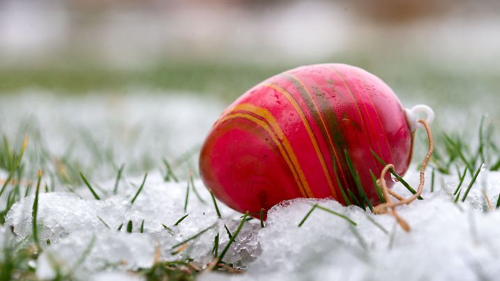 Ein vom Sturm abgerissenes farbiges Osterei liegt am 31.03.2015 zwischen tauenden Schneeresten auf einem Gartengrundstück in Pokrent (Mecklenburg-Vorpommern). Foto: Jens Büttner/dpa +++(c) dpa - Bildfunk+++