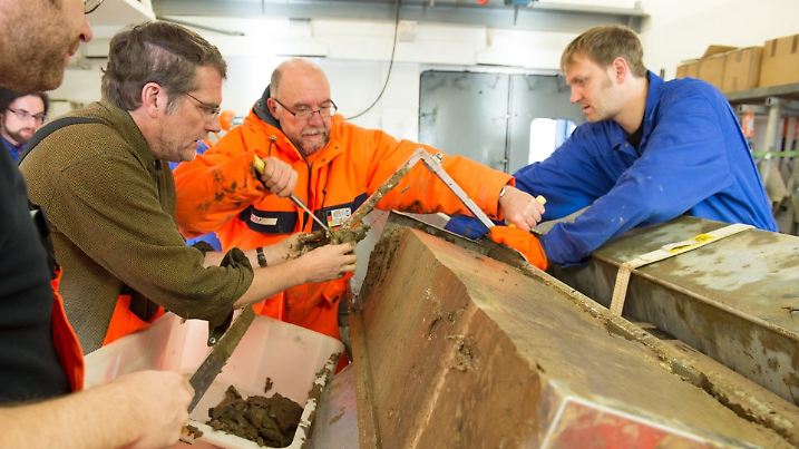 Polarsternfahrtleiter Prof. Dr. Rüdiger Stein (Mitte, orangefarbene Kleidung) und sein Team begutachten im Polarstern-Labor den am Lomonossow-Rücken geborgenen Sedimentkern. Foto: Alfred-Wegener-Institut / Audun Tholfsen, UoB
Taking first samlpes: Polarstern expedition leader Rüdiger Stein (orange clothes) and his team are sampling the valuable sediment core in the lab onboard the research ship Polarstern. Photo: Alfred-Wegener-Institut/ Audun Tholfsen, UoB