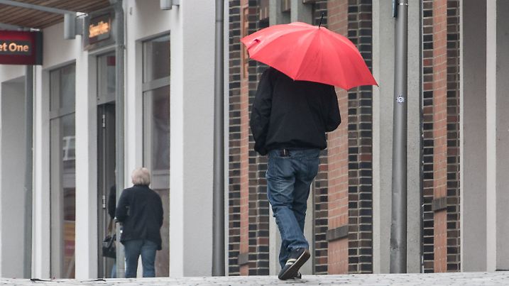 Ein Mann mit Regenschirm geht am 13.05.2016 durch die Innenstadt von Straubing (Bayern). Foto: Armin Weigel/dpa +++(c) dpa - Bildfunk+++