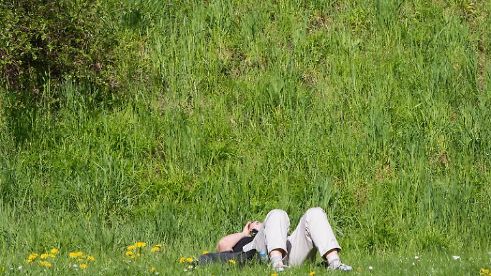 Eine Frau liegt am 20.04.2016 in Eltville (Hessen) beim Kloster Eberbach im Gras und genießt den Sonnenschein im Rheingau. Foto: Frank Rumpenhorst/dpa +++(c) dpa - Bildfunk+++