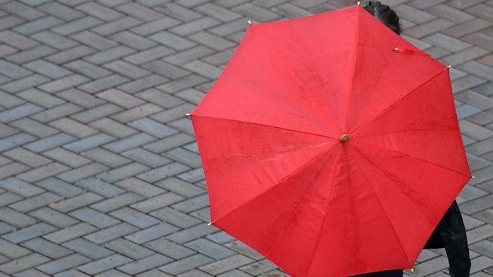 Mit Regenschirm ist eine Passantin am 13.07.2016 in Potsdam (Brandenburg) bei regnerischem Wetter unterwegs. Foto: Ralf Hirschberger/dpa +++(c) dpa - Bildfunk+++