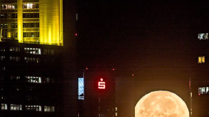 Der untergehende Mond strahlt am 14.11.2016 in Frankfurt am Main (Hessen) früh morgens hinter den Bankentürmen der Stadt. Der Mond kommt der Erde derzeit so nahe wie selten, wodurch er besonders groß erscheint. Foto: Frank Rumpenhorst/dpa +++(c) dpa - Bildfunk+++
