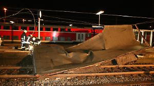 Feuerwehrleute bergen am Donnerstag (18.01.2007) auf Gleis 2 des Hauptbahnhofes in Osnabrück den Teil eines Daches vom Stellwerk, das erst auf die Oberleitung und dann auf das Gleis gefallen war. Die Deutsche Bahn stellt wegen des Orkans "Kyrill" bundesweit den gesamten Zugverkehr ein. Alle Züge würden in die Bahnhöfe gefahren, sagte ein Sprecher der dpa. Wie viele Reisende davon betroffen sind, ist noch unklar. Foto: Friso Gentsch dpa/lni +++(c) dpa - Bildfunk+++