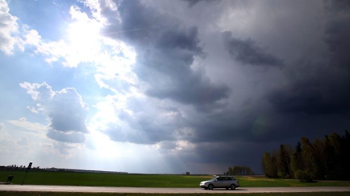 dpatopbilder epa04176153 A car on a road appears to move from thunderstorm (R) to sunshine (L) as it drives near the village of Korma, some 30 kilometers from Minsk, Belarus, 22 April 2014. Temperatures reached up to 21 degrees Celsius in the Minsk region on 22 April, exceeding the normal climatic temperature of 5 to 10 degrees Celsius, local media reported. EPA/TATYANA ZENKOVICH