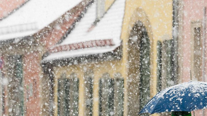 Eine Frau mit Regenschirm geht am 17.04.2017 in Bamberg (Bayern) bei starkem Schneefall über eine Straße. Foto: Nicolas Armer/dpa +++(c) dpa - Bildfunk+++