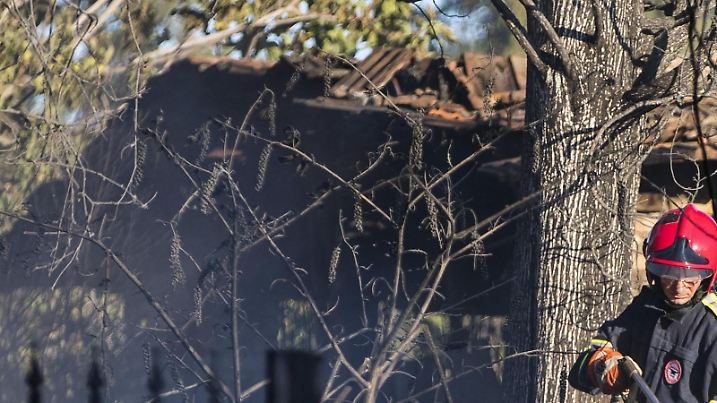 Ein italienischer Feuerwehrmann löscht am 07.08.2017 in Tivoli (Italien) vor einem ausgebrannten Haus Brandnester. Zwei verbrannte Körper wurden in dem ausgebrannten Haus gefunden, nachdem ein Feuer auf einem Feld ausgebrochen war und auf das Haus übergriff. Foto: Angelo Carconi/ANSA/dpa +++(c) dpa - Bildfunk+++