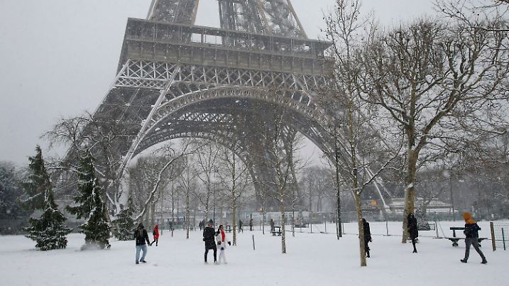 09.02.2018, Paris, Frankreich: Spaziergänger gehen durch den Park Champs de Mars unter dem schneebedeckten Eiffelturm hindurch. Wegen des Schnees durften Touristen nicht auf den Eiffelturm, der bis zum 11.02.2018 geschlossen bleiben soll. Foto: Michel Euler/AP/dpa +++ dpa-Bildfunk +++
