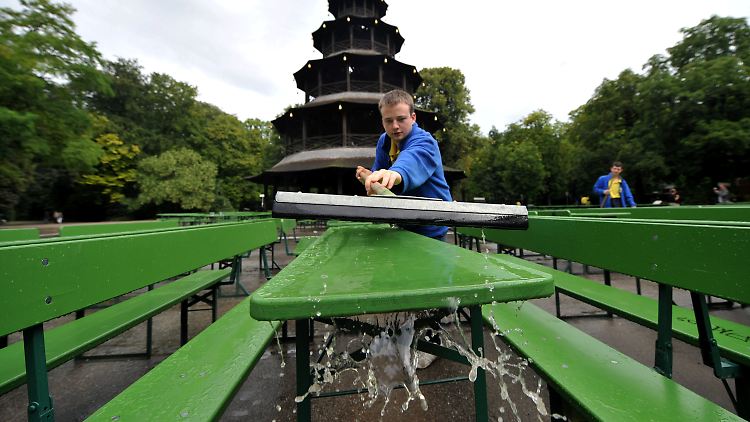 Ein Arbeiter schiebt am Freitag (05.08.2011) das Regenwasser von einem Tisch im Biergarten am Chinesischen Turm im Englischen Garten in München (Oberbayern). Kurze Aufheiterungen und Regenschauer bestimmen das Wetter in Bayern. Foto: Frank Leonhardt dpa/lby  +++(c) dpa - Bildfunk+++