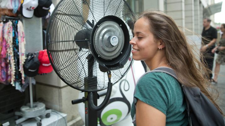 Die aus Portugal stammende Touristin Elena erfrischt sich bei hochsommerlichen Temperaturen an einem Ventilator am 07.08.2015 auf der Straße Unter den Linden in Berlin. Foto: Jörg Carstensen/dpa | Verwendung weltweit