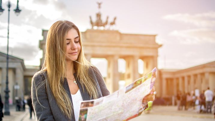 Junge Frau orientiert sich in Berlin mit einer Stadtkarte