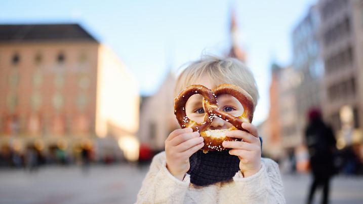 Kinder auf dem Münchner Marienplatz hält eine Bretzel in der Hand