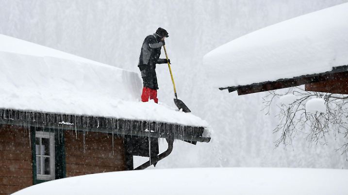 09.01.2019, Österreich, Untertauern: Ein Mann befreit ein Dach von der Schneelast. Die Wetterlage in Bayern und Österreich wird vielerorts zu einer immer größeren Bedrohung. Foto: Helmut Fohringer/APA/dpa +++ dpa-Bildfunk +++