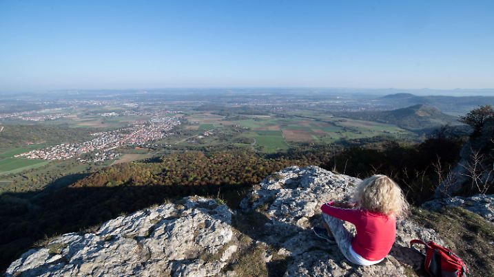 16.10.2018, Baden-Württemberg, Ochsenwang: Eine Wanderin sitzt auf dem Breitenstein am Albtrauf der Schwäbischen Alb und betrachtet die Aussicht. Foto: Marijan Murat/dpa +++ dpa-Bildfunk +++