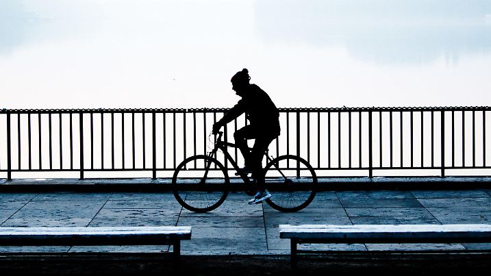 10.10.2018, Niedersachsen, Hannover: Ein Fahrradfahrer fährt am Nordufer des Maschsees entlang, über den am frühen Morgen vor Sonnenaufgang leichte Nebelschwaden wabern. Foto: Julian Stratenschulte/dpa +++ dpa-Bildfunk +++