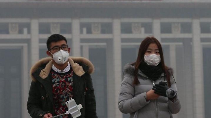 Touristen in Peking tragen Masken, um ihre Lungen vor den alarmierenden Feinstaubwerten zu schützen. Medien und Bevölkerung sind kritischer gegenüber der immensen Luftverschmutzung. Es ist das erste Mal, dass in Peking die Smog-Alarmstufe "Rot" ausgerufen